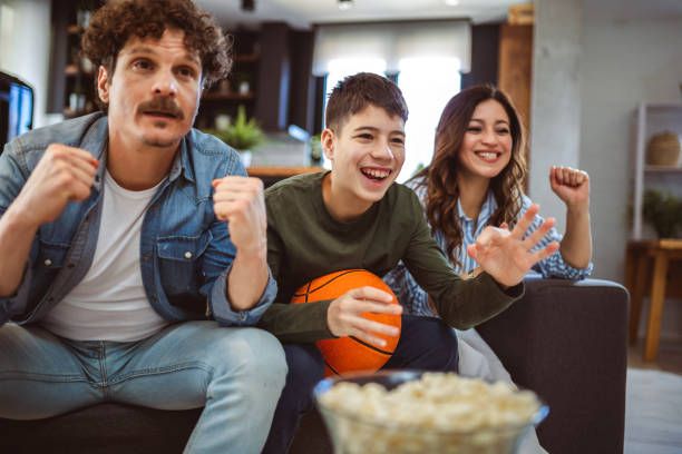 Familia latina viendo partido de baloncesto con palomitas celebrando con servicio IPTV